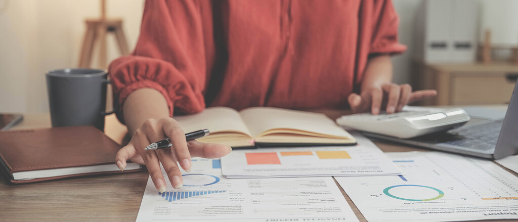 A crowded desk, full of papers, a mug and technology accompanied by text that reads, “4 ways we’re building strong partnerships with bookkeepers like you”.  