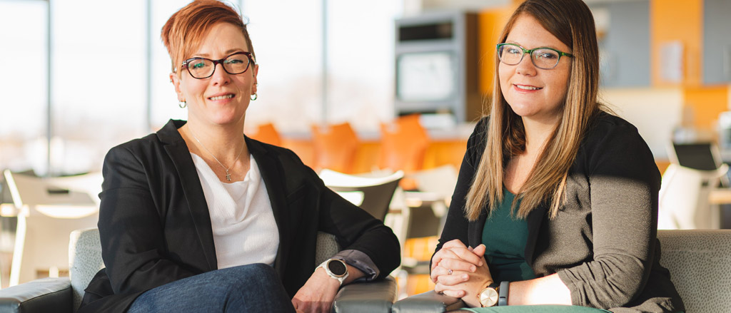 Une photo datant de 2019 montrant Nicole Stewart, vice-présidente des ressources humaines de Payworks, et Candace Synchyshyn, directrice des ressources humaines, assises sur un sofa dans les locaux de Payworks.