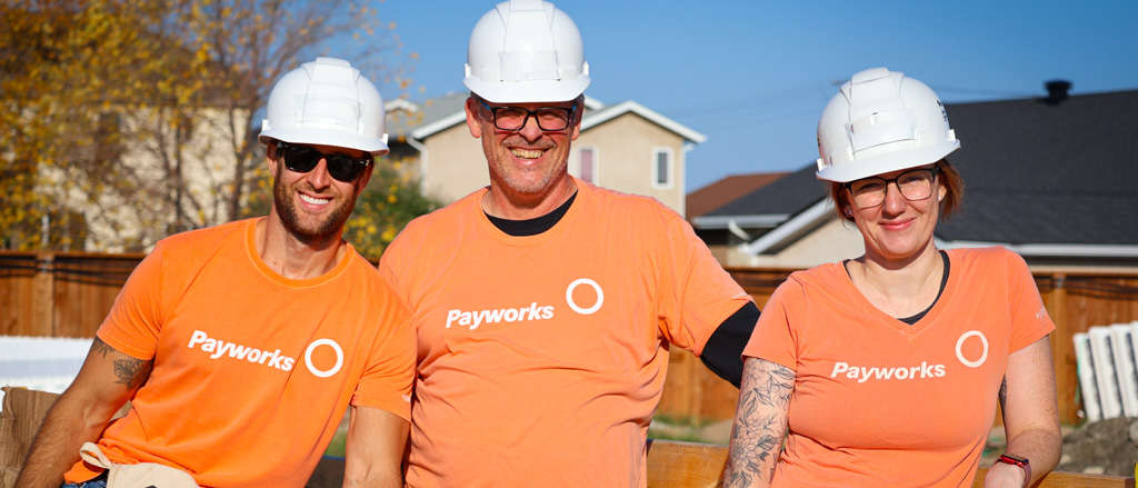 Three staff in Payworks t-shirts and text that reads, "Pay it Forward".  