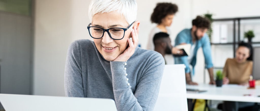 Une femme regarde un écran d’ordinateur portable accompagné du texte suivant : « Professionnels de la paie : vous aimeriez rendre les congés et les licenciements simples comme bonjour? ».