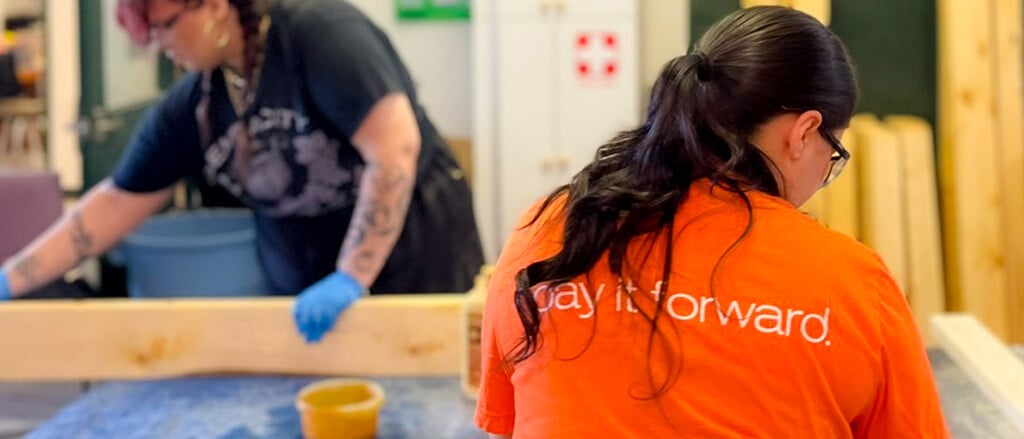 Une employée de Payworks portant un chandail orange Donner au suivant accompagné du texte suivant : « Comment nos solutions peuvent vous aider à faire bouger les choses dans votre communauté ». 