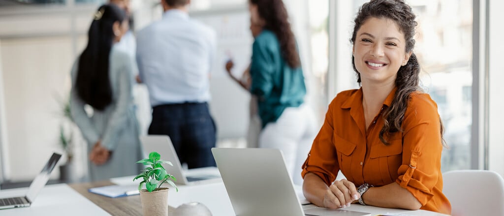 A woman sitting at a laptop computer accompanied by text that reads, “This National Bookkeeping Week, uncover the “ROI” of DEIB”.  