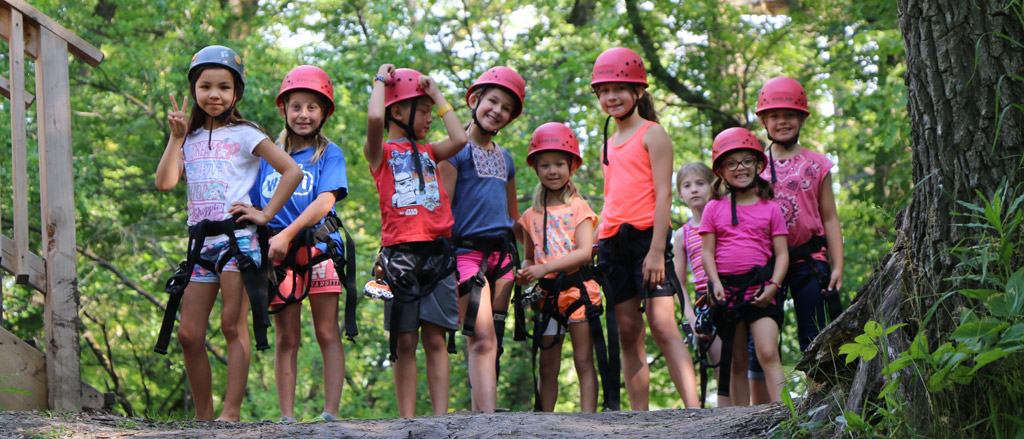 A kid on a zip line. Text reads, “Celebrating diversity, inclusion and belonging with Camp Manitou”.  