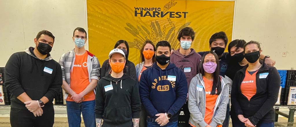 11 Payworks staff volunteering at Harvest Manitoba. Text reads, “Pay it Forward”.  