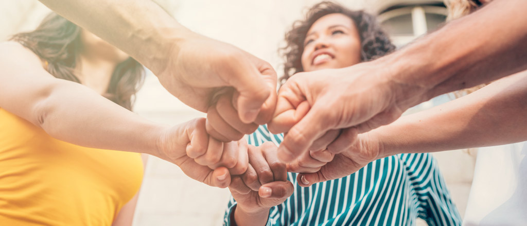 Group of friends showing unity by stacking hands. 