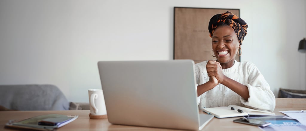 A woman looking happy staring at a laptop accompanied by text that reads, “ICYMI: find new efficiencies & discover tools that will help set you up for the best year yet!”.  