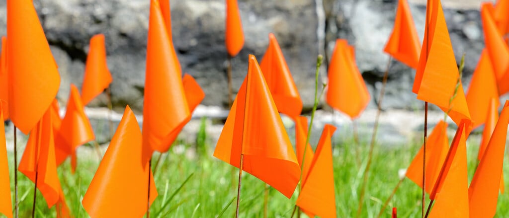 Many orange flags planted in the grass accompanied by text that reads, “National Day for Truth & Reconciliation: stat holiday legislation across the country.  