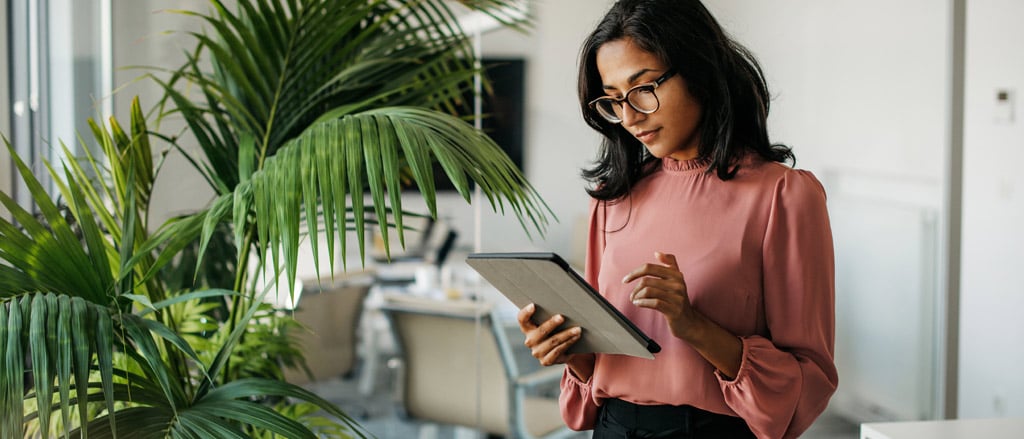 A woman standing looking at a tablet accompanied by text that reads, "Six tips for a smooth year-end".  