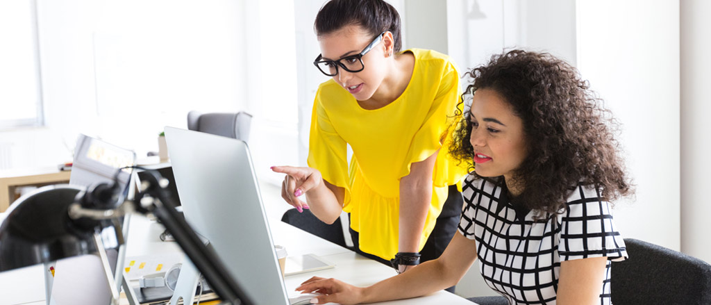 Deux femmes regardent un écran d’ordinateur. Il est écrit : « Traitement de la paie : comment tirer parti de la vignette “Votre journée” sur la page d’accueil Payworks ». 