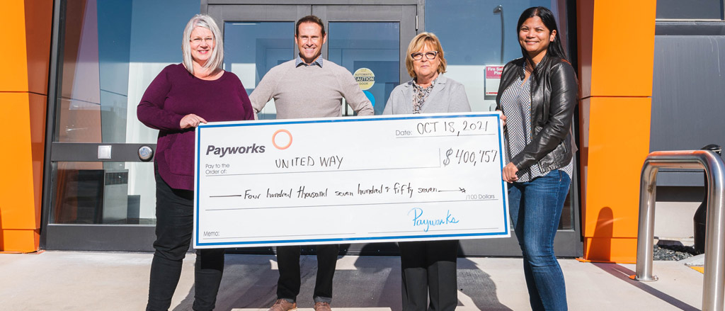 Text reads, "United Way Workplace Campaign: The BIG reveal".  Four of Payworks staff standing outside the front entrance to Payworks while holding a giant presentation cheque in the amount of 400 thousand 757 dollars.