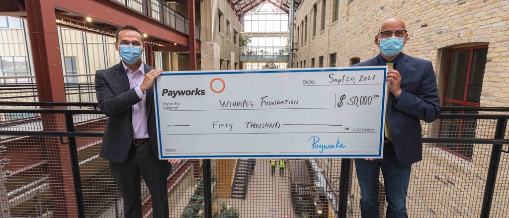 Two individuals holding a large cheque for $50,000. Text reads, “Introducing Payworks Education Award”.  