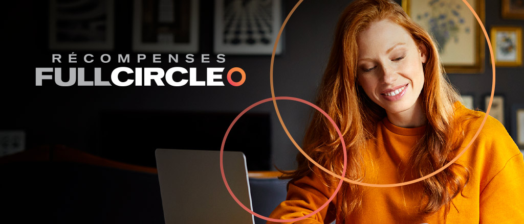 Une femme assise à son bureau chez elle devant un ordinateur portable. Elle regarde vers le bas et sourit. Il est écrit : « Récompenses Full Circle; recompensesfullcircle.ca ». 