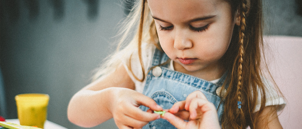 Child doing crafts at a Family Fun Day event where parents are volunteering their time to make a difference in the community. 