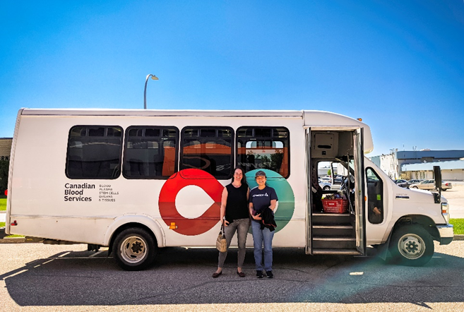 Two Payworks staff in front of a shuttle bus.